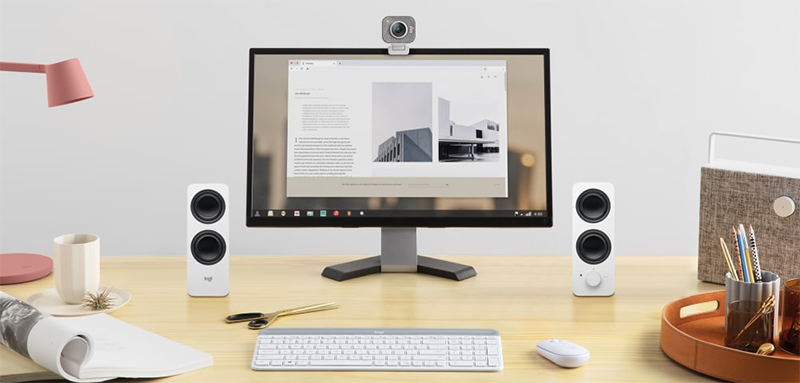 Lifestyle image of speakers on a desktop either side of a PC monitor with keyboard & mouse