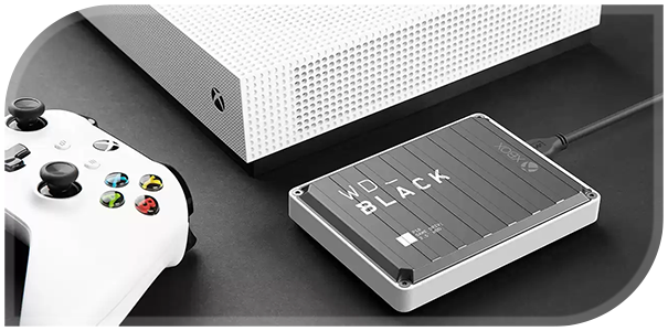 Lifestyle image of WD_BLACK external hard drive on a desk beside a white Xbox