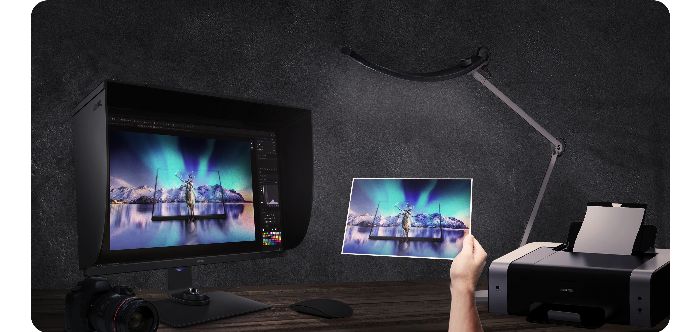 Photographer holding a test print up to BenQ SW321C 4k Monitor for comparison