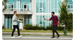 Videographer and host walking along sidewalk capturing video with DJI Osmo and DJI Mic 2