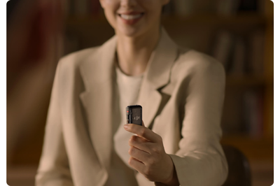 female host holding DJI Mic 2 TX and wearing beige blazer