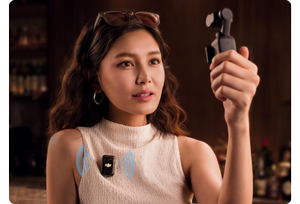 ASian woman holding DJI Osmo pocket camera with DJI Mic 2 attached to woolen jumper