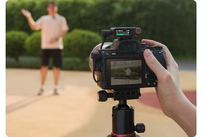 Videographer capturing video of host with mirrorless camera with DJI Mic 2