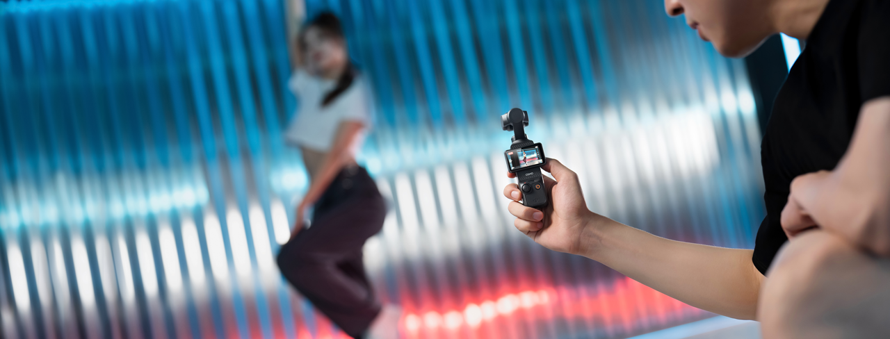 Man kneeling filming a female dancer with DJI Osmo Pocket 3
