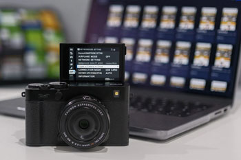 Fujifilm X-E5 sitting infront of Apple Macbook pro with Frame.io open
