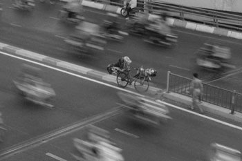 Black and White Sample image of Fujifilm X-E5 of busy street with cyclist in standing in centre