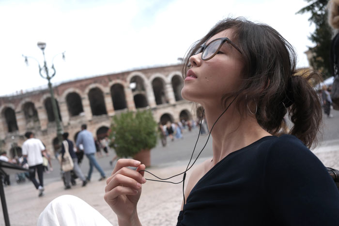 fujifilm X-E5 sample photograph of young woman wearing earphones looking up at the sky