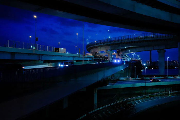 night time photograph of japanese winding highway bridges illuminated by car headlights