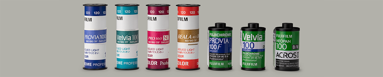 Rolls of Fujifilm medium format film and 35mm film rolls standing in a line, Provia, Velvia, REALA ACE, Acros, Fujichrome,
