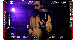 Fuji X100VI video shooting frame of man holding godox light infront of rear purple lighting