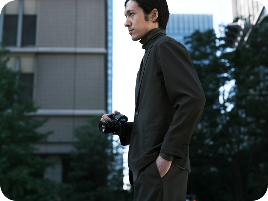 Photographer walking in a city with skyscrapers holding Fujifilm XT5