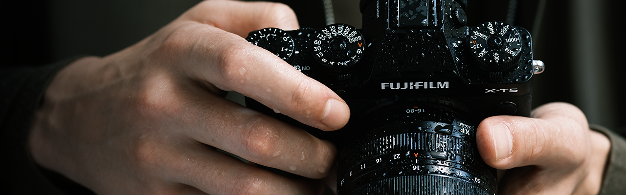 Photographer holding Fujifilm Xt5 sprayed with water droplets