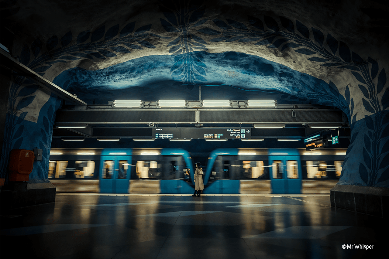 Fuji XT5 sample photograph of a woman stood on a train platform surrounded by a blue and white rock face as a train goes by, Copyright Mr Whisper