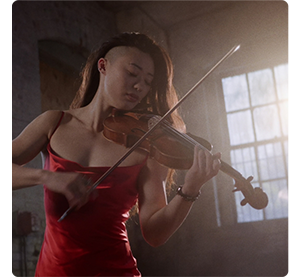 photograph of female violinist wearing red dress standing in front of wood frame window