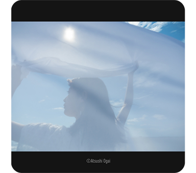 Lumix Leica DG Vario-Elmarit 12-35mm sample image of woman holding sheer fabric cloth overhead in bright sunny day