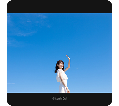 Lumix Leica DG Vario-Elmarit 12-35mm sample image of asian woman wearing white dress standing infront of clear blue sky background