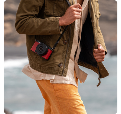 Person walking with Red Panasonic Lumix S9 Camera wearing green denim jacket and orange trousers