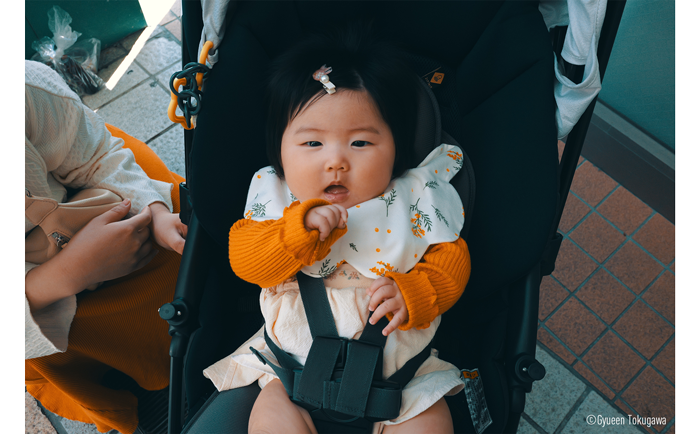 LUMIX S9 and S 26mm Sample Image of baby girl wearing white and orange dress and jumper sat in pram