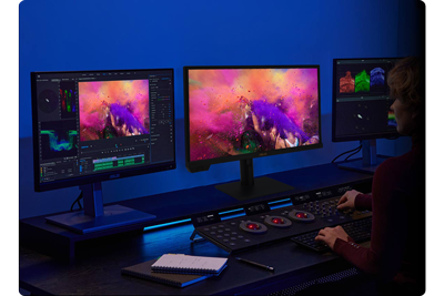 Colourist with a three monitor setup and colour grading wheels