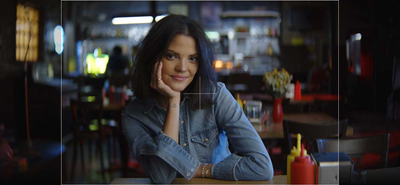 photograph of a woman sat at table in an empty diner bar wearing a denim shirt, 3:2 Full frame gate overlayed on top of frame