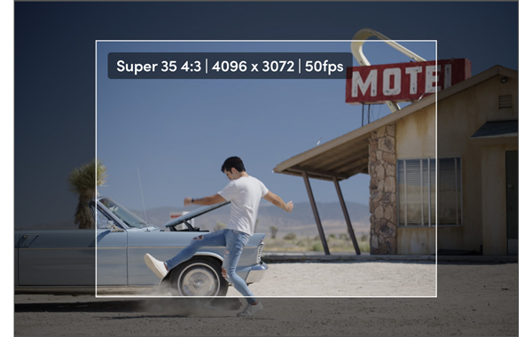 Super 35 4:3 still of a man kicking dust in front of a car in a motel parking lot