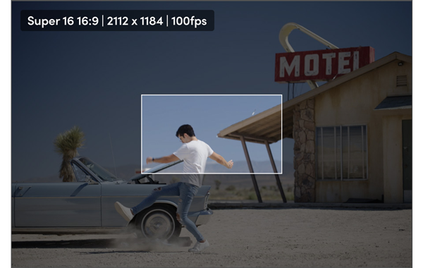 Super 16 16:9 still of a man kicking dust in front of a car in a motel parking lot