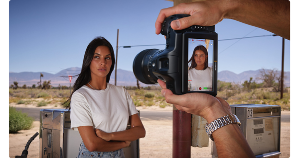 videographer recording woman stood at gas station pumps in the desert with vertical video