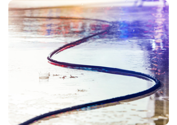 a black SMPTE fiber optic cable snakes across the ground outside where it is raining heavily