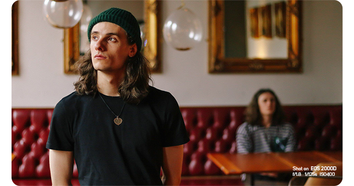 Canon EOS 2000D sample photo of a man in a cafe wearing a beanie