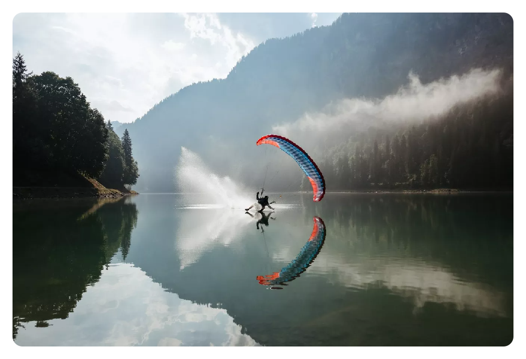 photo of somone paragliding across a lake surrounded by forrest taken with the canon r6 mark ii