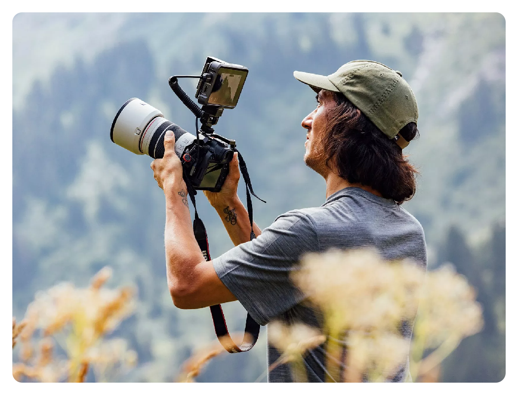 someone using the canon r6 mark ii with a monitor attached to the top and a telephoto lens