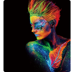 photograph of model painted in luminescent oranges, greens and blues on black background