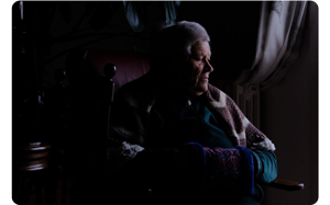 sample photograph of elderly man sitting in chair in dark room