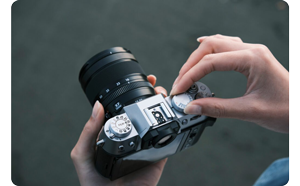 Fujifilm X-T50 silver camera with control dials being adjusted by female photographer hands