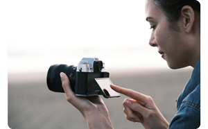 female photographer holding Fujifilm X-T50 with LCD screen flipped up