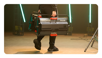 someone carry the godox led light across a set