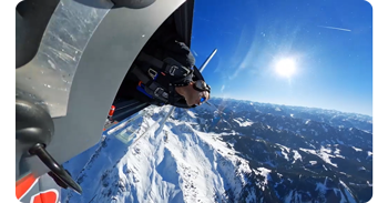 photograph from stunt plane cockpit with pilot performing barrelroll over mountain range