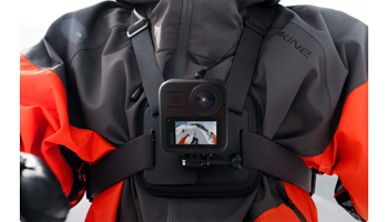 Snowboarder wearing grey and orange jacket with GoPro MAX 360 Camera chest mounted