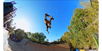 Skateboarder performning Melon grab in the air over a large vert halfpipe