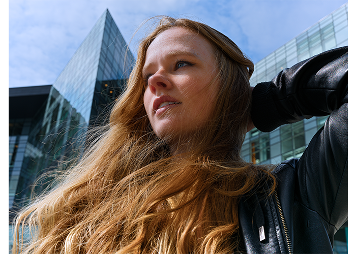 Hasselblad X2D 100C Lightweight Field Kit Sample Image close up portait of woman with long hair stood infront of tall glass skyscrapers