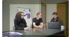 3 people sitting at a table conducting a meeting with apple macbook open