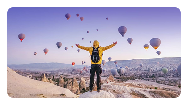 someone standing over a hilltop with hot air balloons