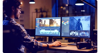 Video editor working on timeline on dual monitor workstation at night in a New York loft
