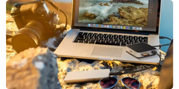 OWC USB-C Travel Dock, Macbook and carmera sitting on rock in bright sunshine