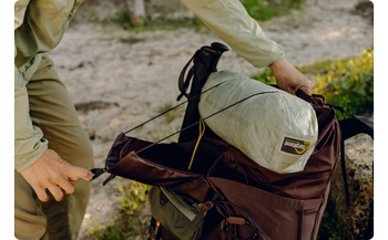 person using Ultra Cinch Roll Top on White Peak Design Outdoor Backpack