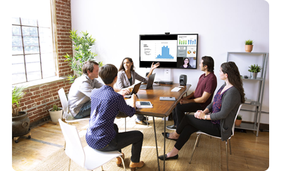 5 people sitting around a meeting room table with a presentation display in the background