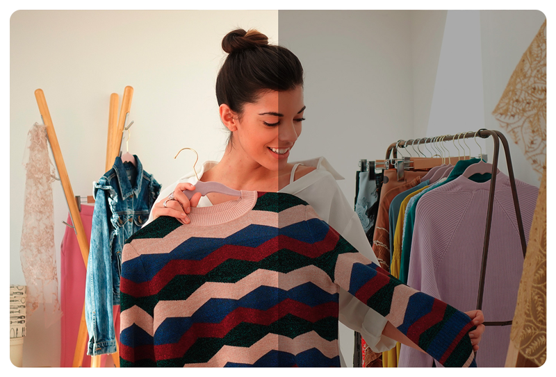 Woman holding blue, red and pink striped sweatshirt infront of her clothes rack