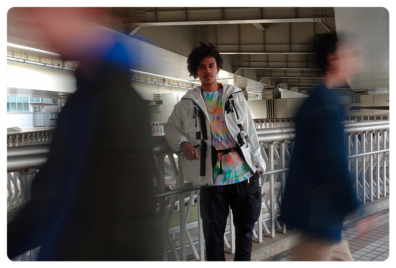 long exposure photograph of man stood in pedestrian walk way with other people blurred