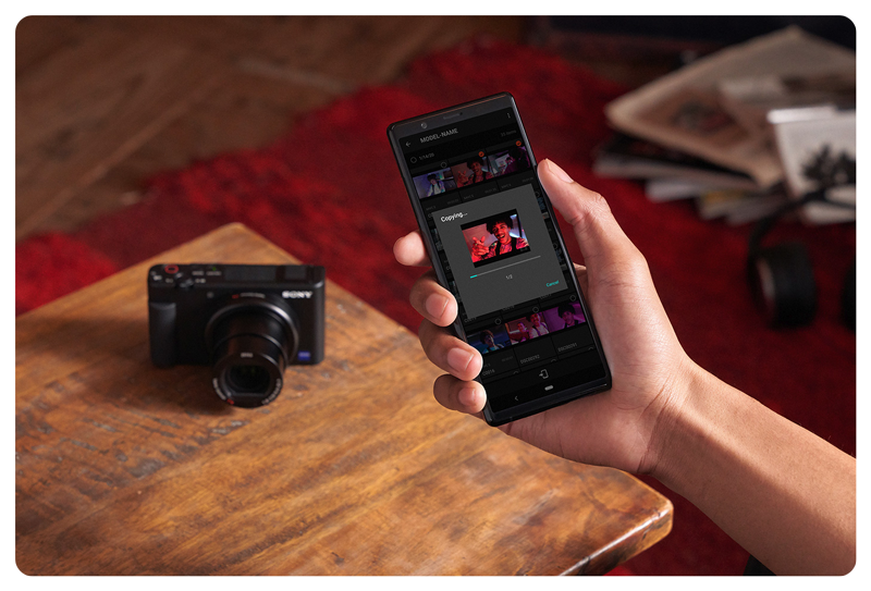 person using smartphone app imaging edge paired with Sony ZV-1 Vlog Camera on a coffee table