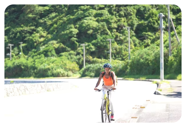 man wearing orange tank top riding bicycle in a park
